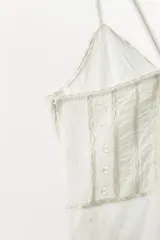 Vestido corto de viscosa y algodón, con escote en pico y tirantes finos cruzados en la espalda. Presenta un diseño con pliegues, aplicaciones de lazadas a contraste y falda con volantes en el bajo.