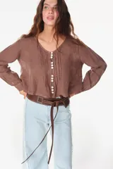 Camisa blanca de lino italiano, de manga larga, escote en V y cierre frontal con múltiples botones y detalles de alforzas.