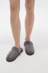 Pantuflas cerradas color marrón con ribetes de piel sintética en la abertura y suela plana.