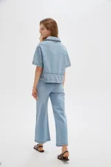 Blusa de jean de manga corta, corte holgado, con cuello en V, cierre frontal con botones y detalles de frunces.