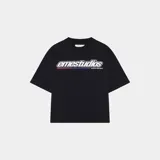 Camiseta negra de corte holgado con estampado frontal del logo "emestudios" en blanco con contorno negro y líneas horizontales en rojo, azul y blanco. Debajo del logo, la frase "ALWAYS GRATEFUL".