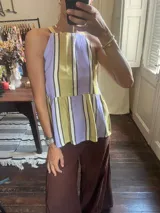 Top sin mangas con cuello halter, diseño a rayas verticales en tonos lila, verde oliva y blanco, con un corte peplum en la cintura.