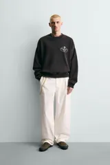 Sudadera de corte relajado color negro con efecto lavado, cuello redondo, manga larga y puños en rib. Presenta un estampado gráfico a contraste en el pecho con el texto 'General Service Goods'.