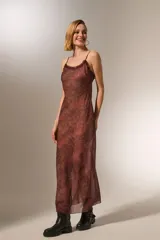 Vestido midi de poliéster con estampado animal print, breteles finos y volados en el escote. Corte al cuerpo y cuello redondo.