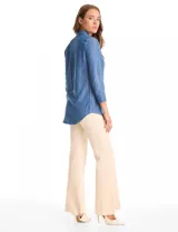 Blusa de lyocell color azul con efecto denim, cuello camisero con solapa y escote en V con cierre de un botón. Presenta mangas largas con terminación doblada y ruedo redondeado.