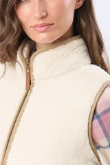 Chaleco de tejido sherpa color beige, con cuello alto y detalles en eco cuero. Diseño sin mangas que proporciona abrigo al torso manteniendo la libertad de movimiento.