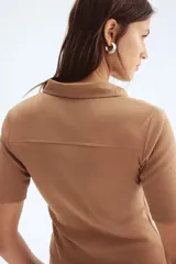 Top de punto color camel, ajustado al cuerpo, con cuello camisero, tapeta de botones y costuras decorativas frontales.