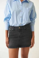 Minifalda de denim negro con tiro bajo, corte recto y bolsillos funcionales.
