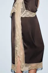 Falda midi de tiro medio, color marrón oscuro, con detalle de encaje color beige a contraste en el bajo y abertura lateral.