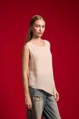 Musculosa de poliéster color natural, sin mangas, con cuello redondo y diseño asimétrico.
