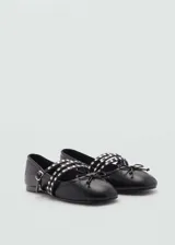 Zapato tipo ballerina color negro, con punta redondeada y triple tira con hebilla y tachas plateadas.