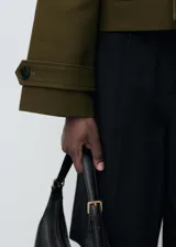 Chaqueta corta de doble botonadura en color verde militar, con cuello de solapa, bolsillos laterales, trabillas en los hombros y mangas largas con puños abotonados.