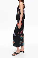 Falda midi de corte recto con cintura elástica y estampado de paisajes marinos en tonos coloridos sobre base negra.
