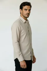 Camisa de poliéster color marrón, de corte holgado, con mangas largas, cuello camisero clásico y cierre frontal de botones.