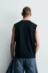 Camiseta tank de punto de algodón, color negro, de corte relaxed fit con cuello redondo, manga sisa y acabados irregulares.
