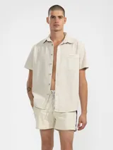 Short de baño para hombre color azul marino, con calce relajado y una tira lateral blanca estilo tuxedo. Presenta cintura elástica con cordón regulable, bolsillos laterales y trasero con cierre.