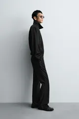 Cazadora bomber negra con textura arrugada, cuello solapa, hombreras marcadas, manga larga con puño abotonado, bolsillos de vivo en la cadera, bajo elástico y cierre frontal con cremallera.