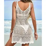 Vestido corto de playa color blanco, confeccionado en tejido calado con diseño geométrico y floral. Es de corte recto al cuerpo, sin mangas, con escote redondo y un tajo lateral.