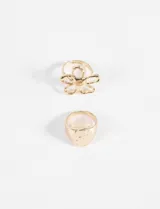 Set de dos anillos dorados: uno con forma de flor y otro con forma de sello circular con textura machacada.