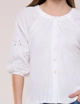 Blusa Liv Los Angeles de color blanco, confeccionada con torso de modal y mangas tres cuartos con detalles de bordado calado. Presenta cuello redondo con apertura central y cierre frontal de botones.