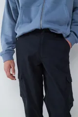 Pantalón cargo tipo jogger color negro, con bolsillos laterales con solapa, cintura con cierre y botón, y puños elásticos en los tobillos.