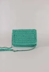 Cartera bandolera color verde agua, tejida a crochet con trapillo reciclado. Tiene correa de cadena plateada y cierre con botón imán.
