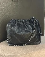 Bolso tipo shopper de cuero negro con diseño acolchado en patrón de rombos. Cuenta con cierre superior fruncido y correa de cadena metálica entrelazada con cuero.
