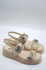 Sandalia de plataforma color beige claro, con dos tiras anchas con estampado de piel de serpiente (pitón) y hebillas metálicas.