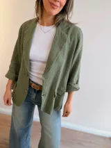 Blazer de lino color beige, de corte relajado y líneas clásicas. Presenta cuello con solapas, cierre frontal con dos botones y bolsillos con solapa en el frente.