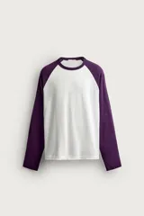 Remera manga larga de corte regular fit, con diseño estilo raglán en color blanco y mangas en color violeta oscuro.