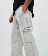 Pantalón de jean corte baggy con bolsillos cargo laterales, cierre de botón y cremallera, y cintura con trabillas.