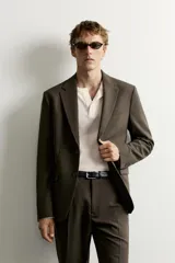 Blazer slim fit de corte sastrero en color verde oscuro, con cuello de solapa de muesca, bolsillos con solapa en la cadera y cierre frontal de botones.