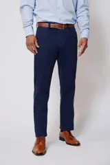 Pantalón de vestir azul marino, de corte recto, con bolsillos laterales y traseros. Se ajusta a la cintura con cinturón de cuero marrón.