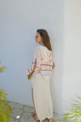 Falda larga tejida color marrón con brillo metálico, corte al cuerpo, abertura alta en la pierna y recortes laterales con cordones ajustables.