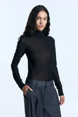 Polera de microtul elastizado color negro, con cuello alto y puños tejidos acanalados a tono. Presenta un diseño ajustado al cuerpo y mangas largas.