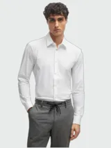 Camisa blanca de manga larga con corte slim fit, confeccionada en punto elástico técnico, con cuello clásico y cierre frontal de botones.