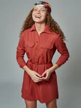 Vestido camisero color verde óxido, con cuello camisero, mangas largas con puños abotonados, dos bolsillos con solapa en el pecho, cinturón de lazo y cierre frontal con botones.