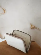 Billetera Actitud Sur de cuero con pelo vacuno en color blanco, con cierre perimetral y compartimentos internos de cuero.