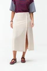 Falda midi de lino color beige, de tiro alto y corte recto, con abertura delantera y cierre cruzado sutil.
