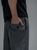 Pantalón cargo de corte oversize confeccionado en microfibra técnica. Presenta cintura elástica, bolsillos laterales y un bolsillo cargo con cierre de broche snap. Incluye un sistema de elásticos con tancas en los tobillos para regular la apertura y la silueta.