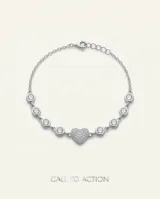 Pulsera de plata 925 compuesta por una cadena delicada intercalada con circonias blancas en chatón y un dije central en forma de corazón completamente pavimentado de circonias.