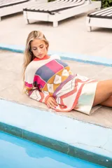 Sweater de punto con diseño geométrico multicolor y cuello redondo. El borde del cuello, puños y ruedo es de color salmón fluorescente.