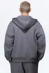 Campera con capucha de felpa gris oscuro, con interior cepillado suave. Modelo de hombros caídos, cierre frontal, bolsillos canguro delanteros y puños y bajo en punto acanalado.