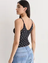 Musculosa negra con estampado floral rosa, breteles finos y escote en V.
