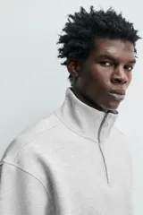 Sudadera roja de corte regular, con cuello alto y cierre frontal de cremallera. Manga larga y terminaciones en rib.