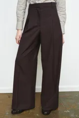 Pantalón de tiro medio con diseño de pierna ancha y estampado de cuadros pequeños. Presenta pinzas frontales, trabillas en la cintura, bolsillos laterales ocultos y cierre frontal con cremallera, botón y ganchos metálicos.