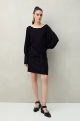 Vestido corto color dorado de punto con brillo integrado en la trama. Diseño de mangas amplias, falda ajustada y lazo frontal que acentúa la cintura.