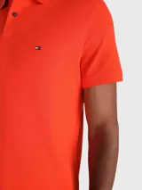 Chomba naranja de Tommy Hilfiger, corte regular, con cuello tipo chomba, cartera de dos botones, logo de la marca bordado en el pecho y mangas cortas.