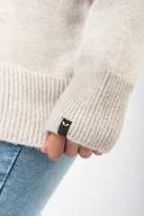 Sweater de punto en color beige, con cuello redondo y diseño de calce relajado. Presenta puños y ruedo acanalados.