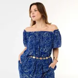 Blusa azul de crepé con estampado floral blanco, diseño fluido con escote off-shoulder y mangas cortas abullonadas.